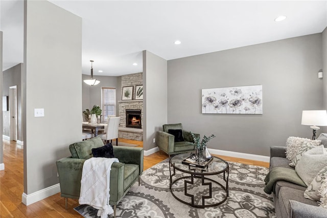 living area featuring light wood finished floors, recessed lighting, baseboards, and a fireplace