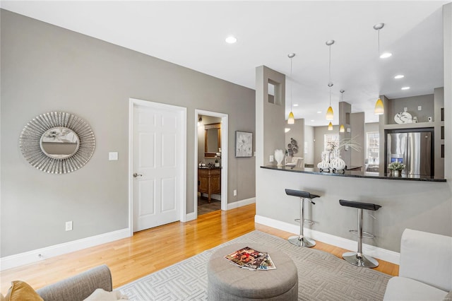 living area with wood finished floors, recessed lighting, and baseboards