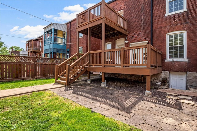 back of house with a deck, brick siding, and fence