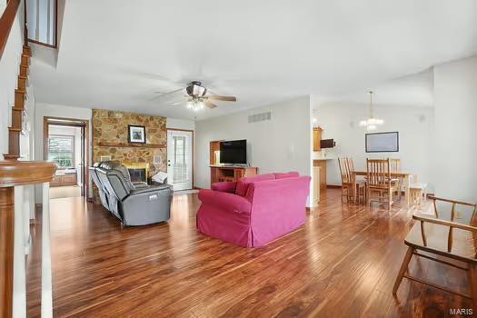 living room featuring a ceiling fan, plenty of natural light, wood finished floors, and a fireplace