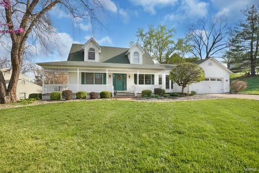 view of front of home featuring a front yard, driveway, an attached garage, and covered porch