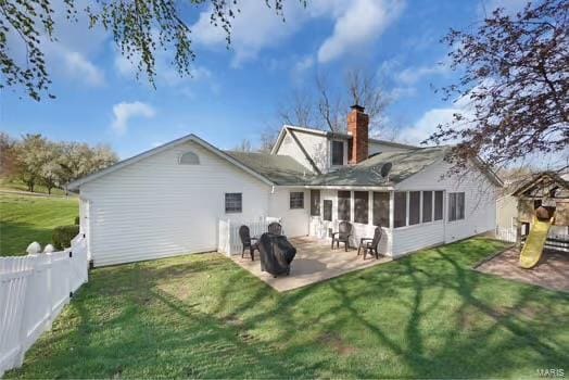 rear view of house with a chimney, fence, a patio area, a yard, and a sunroom