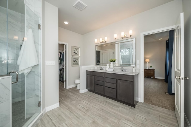 full bathroom featuring a notable chandelier, a sink, a spacious closet, double vanity, and a stall shower