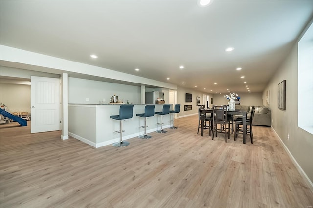 dining room featuring recessed lighting, light wood finished floors, baseboards, and bar
