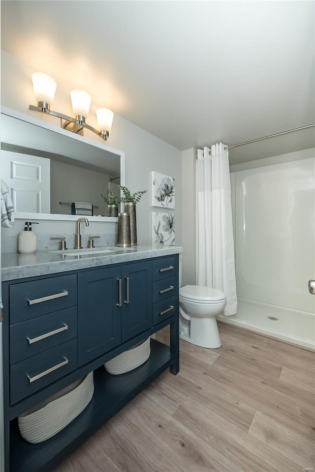 full bathroom featuring vanity, a shower with curtain, toilet, and wood finished floors