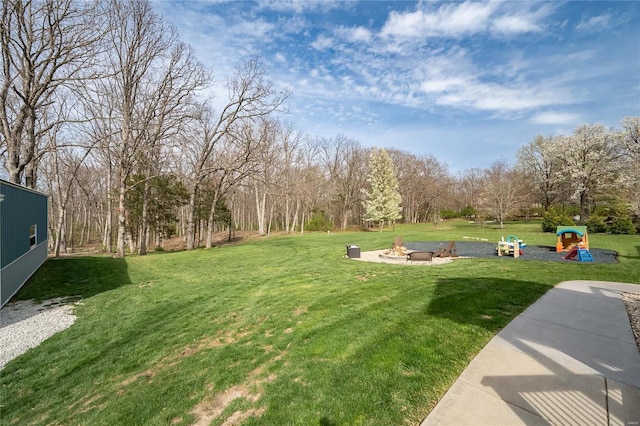 view of home's community featuring playground community, a fire pit, and a lawn