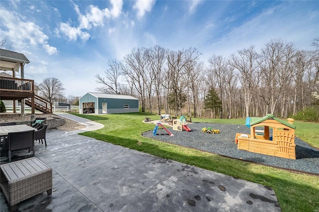 community playground with a yard, a patio area, and an outbuilding