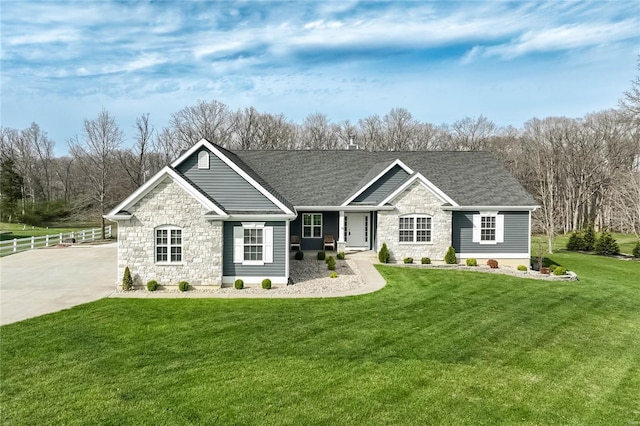 ranch-style home with a front lawn, a shingled roof, and stone siding