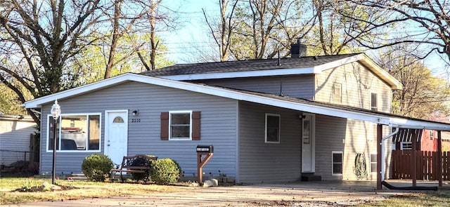 view of front of house with a carport, a chimney, and fence