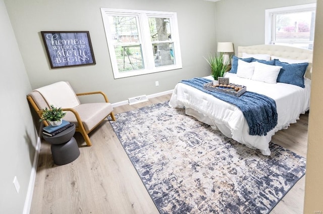 bedroom with wood finished floors, baseboards, and visible vents