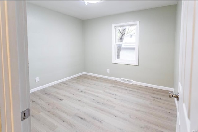 empty room featuring light wood finished floors, visible vents, and baseboards