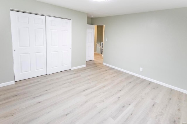 unfurnished bedroom featuring a closet, baseboards, and wood finished floors