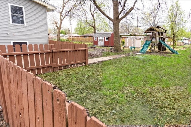 view of yard featuring an outbuilding, fence, a shed, and a playground