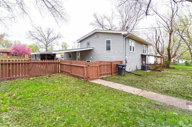 rear view of property with fence, central AC unit, and a lawn