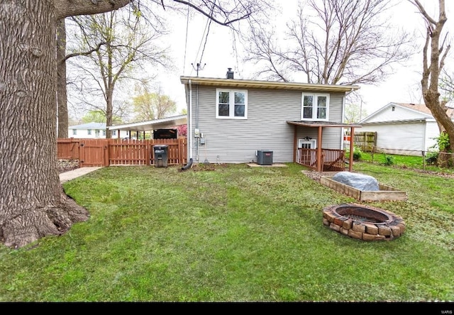 back of house featuring a fire pit, central air condition unit, fence, and a lawn