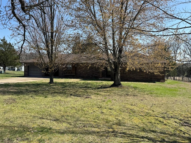 view of front of home with brick siding, a front lawn, an attached garage, and driveway