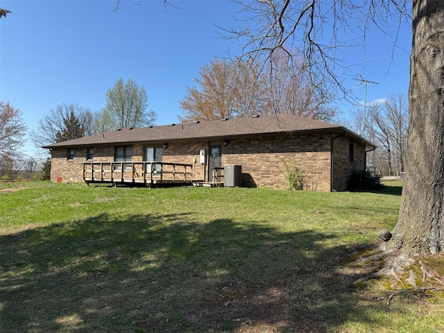 back of house featuring a yard, a deck, and brick siding