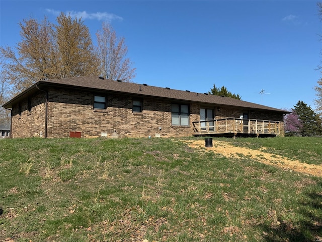 exterior space featuring brick siding, a deck, and a yard