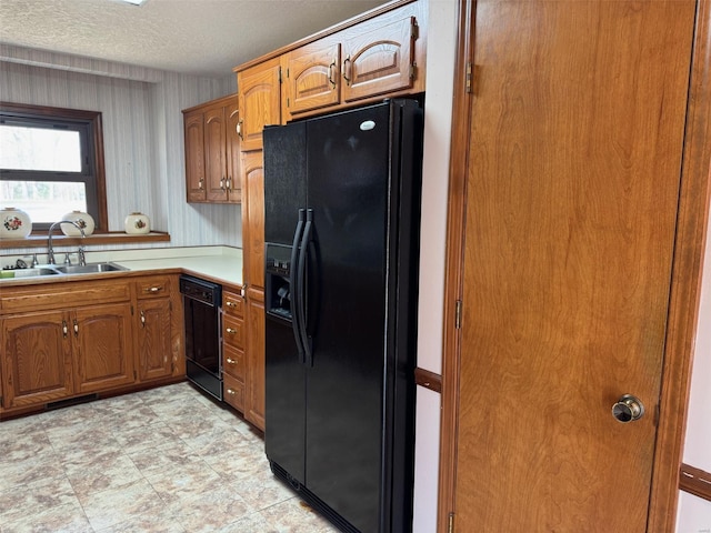 kitchen with light countertops, brown cabinets, a sink, and black appliances