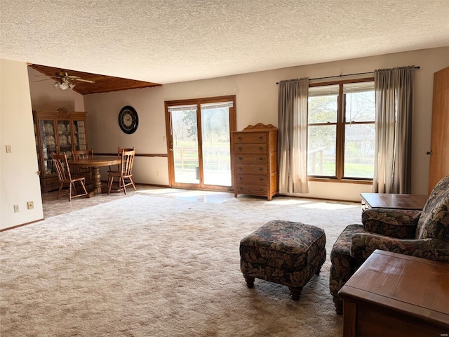 living area featuring a textured ceiling, a ceiling fan, and carpet floors
