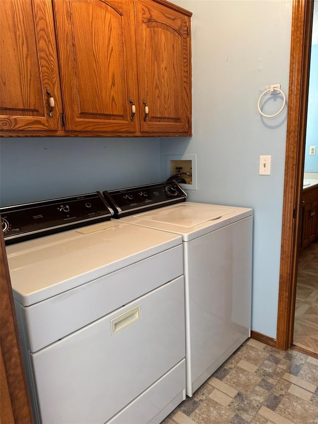 clothes washing area featuring cabinet space, washing machine and clothes dryer, and baseboards