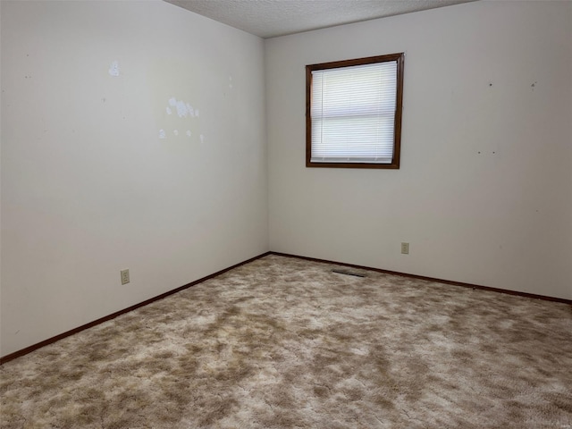 carpeted empty room featuring visible vents, a textured ceiling, and baseboards