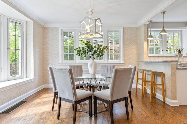 dining space with visible vents, ornamental molding, an inviting chandelier, and wallpapered walls