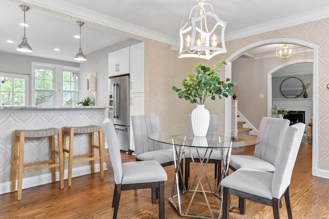 dining space featuring arched walkways, light wood-type flooring, wallpapered walls, a chandelier, and recessed lighting