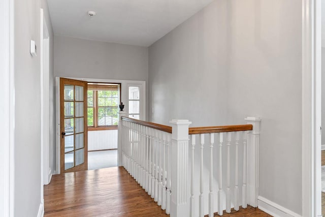 hall featuring baseboards, wood finished floors, and an upstairs landing