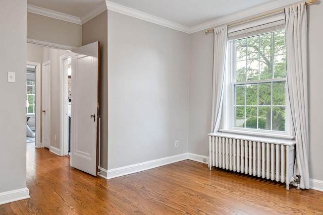 empty room featuring ornamental molding, plenty of natural light, wood finished floors, and radiator