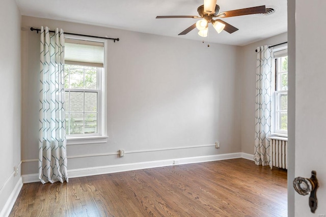 empty room with wood finished floors, radiator heating unit, and a wealth of natural light