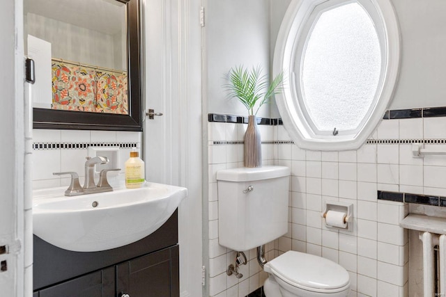 full bath with toilet, tile walls, and a sink