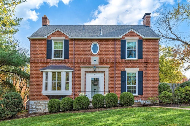 view of front of home with a chimney and brick siding