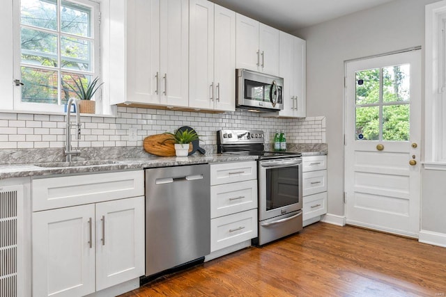 kitchen featuring a sink, appliances with stainless steel finishes, plenty of natural light, and white cabinetry