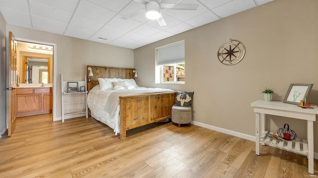 bedroom with baseboards, visible vents, a drop ceiling, and light wood-style flooring