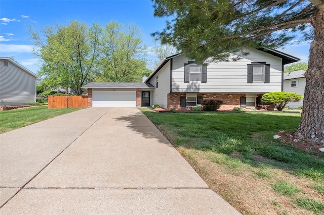 split level home with a garage, fence, a front yard, brick siding, and driveway
