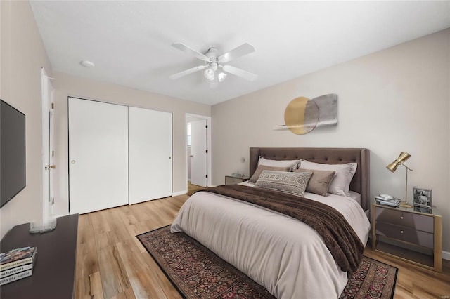 bedroom with light wood-type flooring, ceiling fan, and a closet