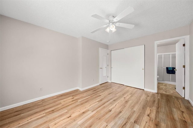 unfurnished bedroom featuring ceiling fan, light wood-type flooring, baseboards, a closet, and ensuite bath