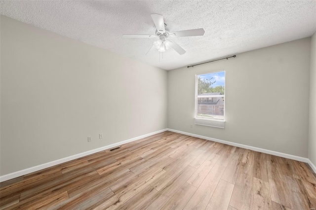 spare room featuring visible vents, wood finished floors, baseboards, ceiling fan, and a textured ceiling