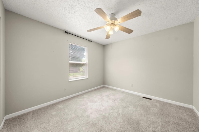 spare room with carpet flooring, a textured ceiling, baseboards, and visible vents