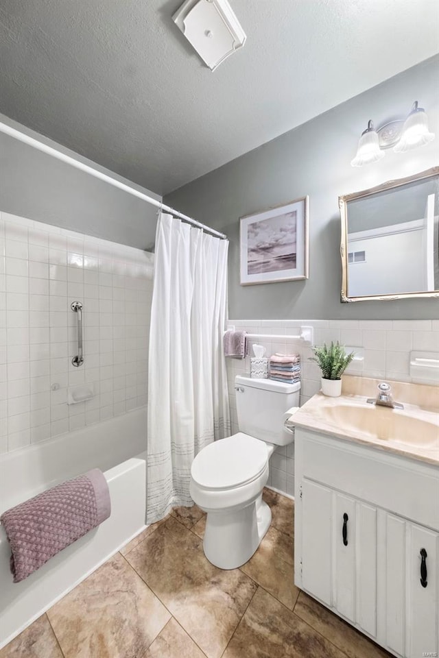 full bathroom featuring tile patterned flooring, vanity, toilet, a textured ceiling, and tile walls