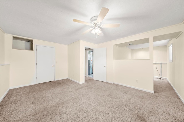 carpeted spare room featuring baseboards and a ceiling fan