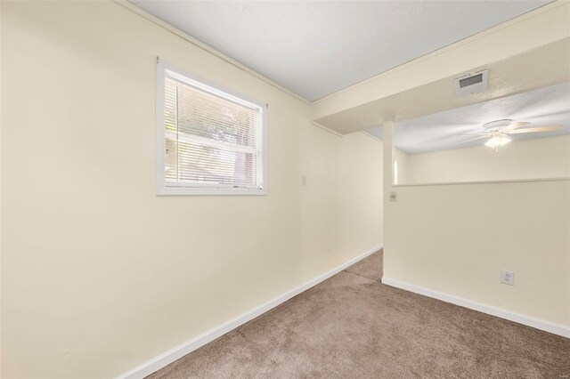 empty room with carpet floors, baseboards, a ceiling fan, and visible vents