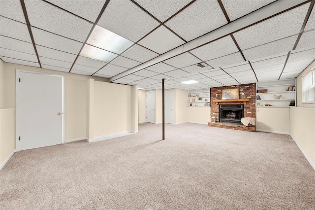 finished basement with carpet floors, baseboards, built in shelves, and a brick fireplace