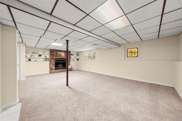 basement featuring baseboards, a drop ceiling, and carpet