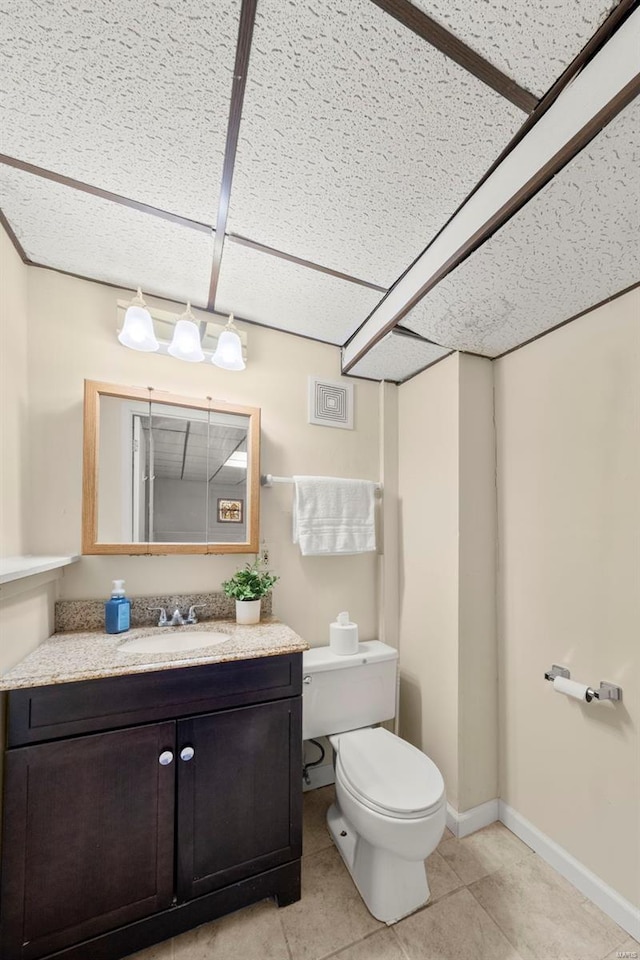 half bathroom with vanity, baseboards, toilet, and tile patterned flooring
