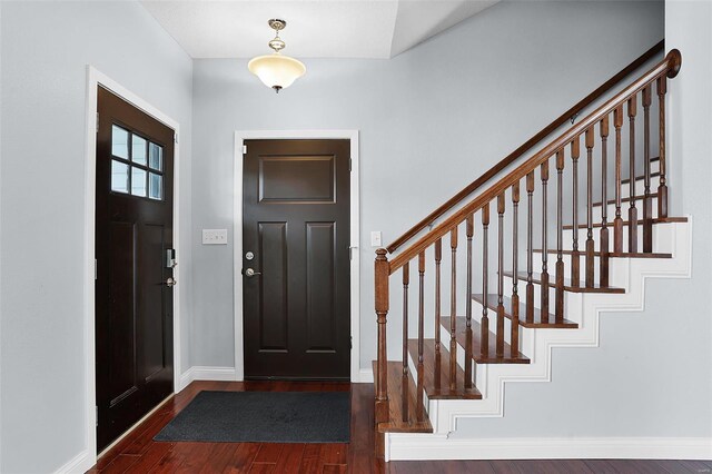 foyer entrance featuring baseboards, wood finished floors, and stairway