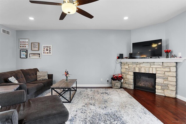 living area with recessed lighting, ceiling fan, visible vents, a stone fireplace, and wood finished floors