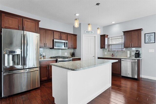 kitchen with decorative backsplash, dark wood finished floors, appliances with stainless steel finishes, decorative light fixtures, and light stone counters