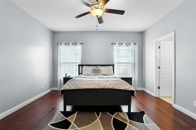 bedroom featuring dark wood finished floors, baseboards, visible vents, and a textured ceiling